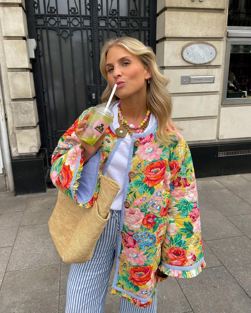 Mujer por la calle con la parka floral Miranda, pantalón de rayas y bolso de rafia