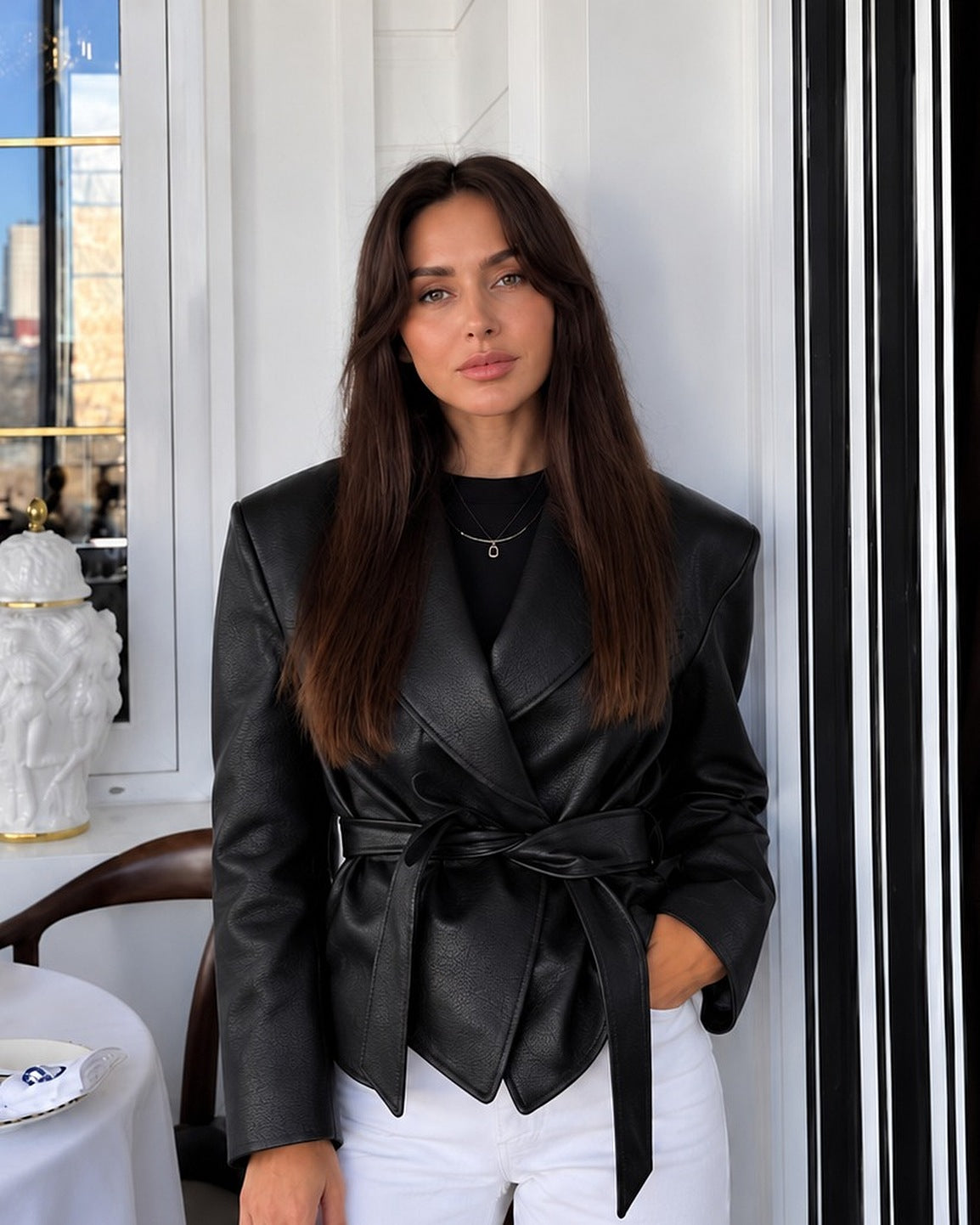 Chaqueta cruzada con cinturón en negro, con camiseta negra y vaqueros blancos anchos