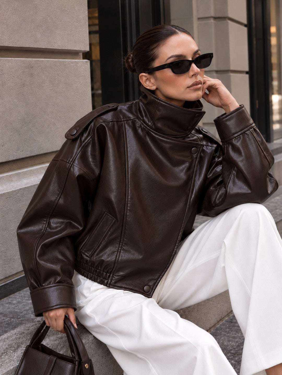 Cazadora efecto piel oversize marrón con cuello alto, sentada, de cerca